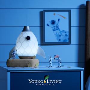 Picture of three astronaut figures around a diffuser shaped like a rocket. Text: Young Living Essential Oils
